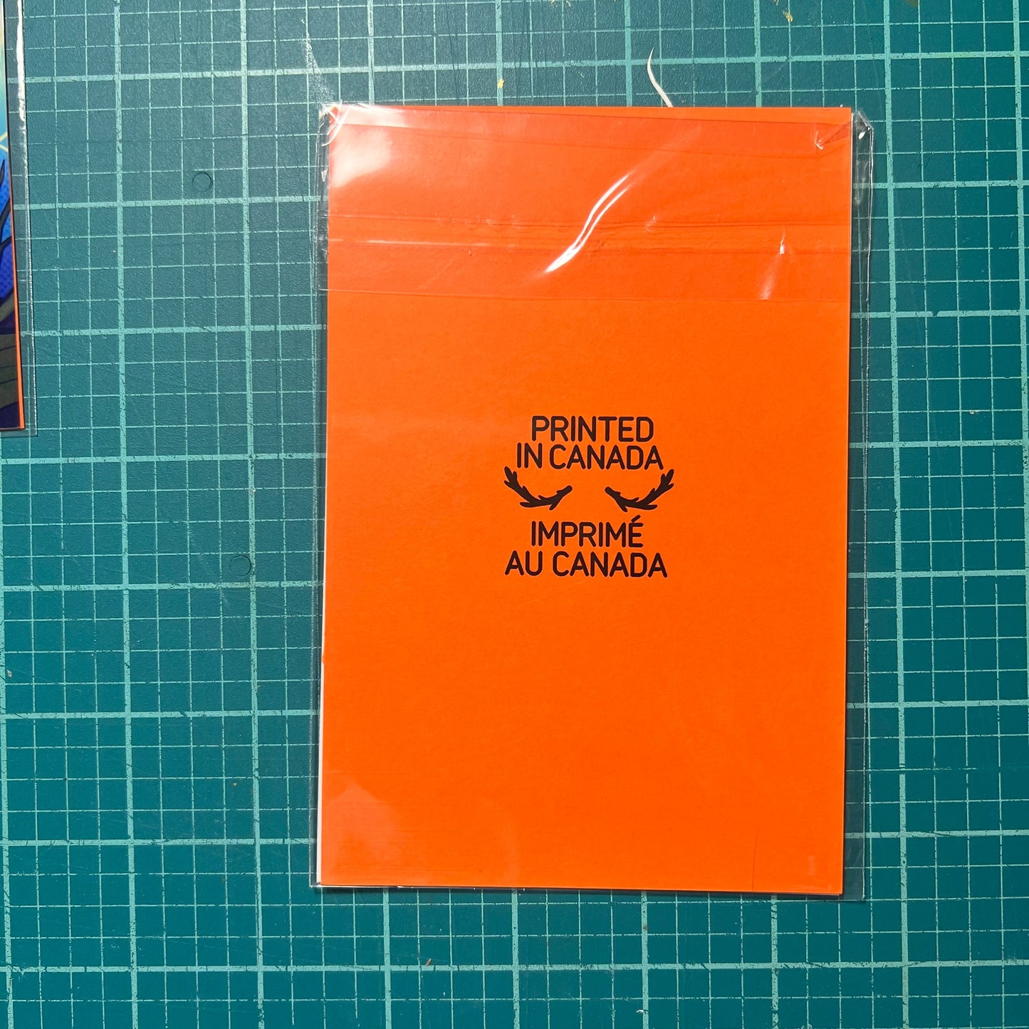 Orange sheet of paper with 'Printed in Canada' text on a grid background