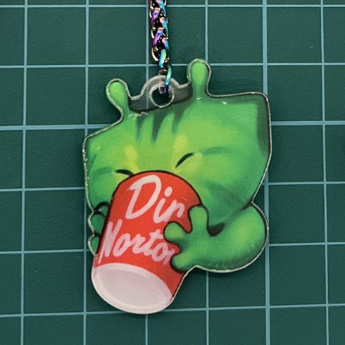 Three colorful acrylic keychain charms displayed on a green cutting mat with measurement markings. The set includes a purple fox head charm, a green dinosaur holding a red drink charm with a metal clasp, and a holographic star and cloud charm set with a yellow star.